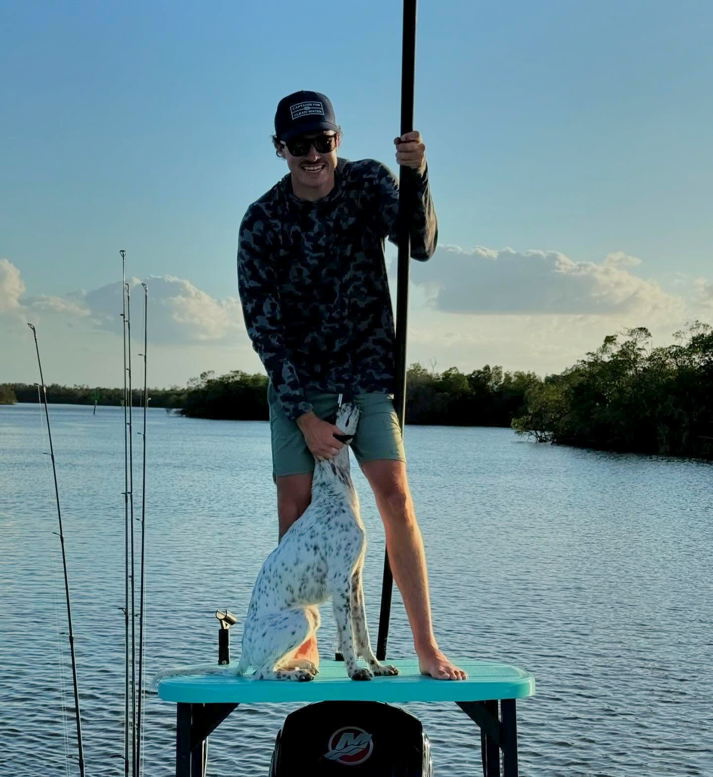 Pierce August poling the skiff with his dog on the bow
