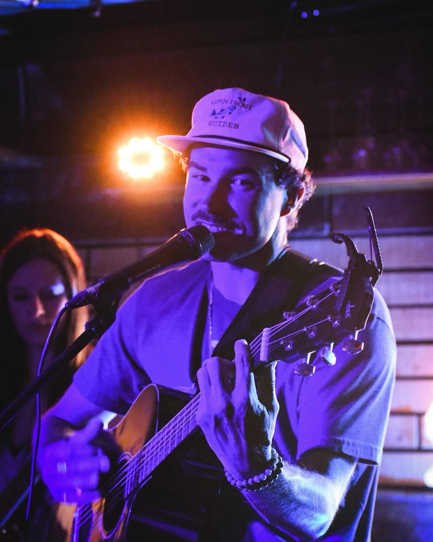 Close-up of Pierce August singing on stage in purple stage light