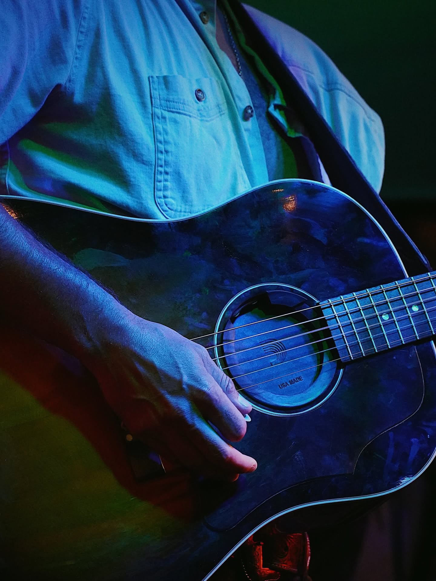 Close-up of Pierce August's hand playing acoustic guitar on stage