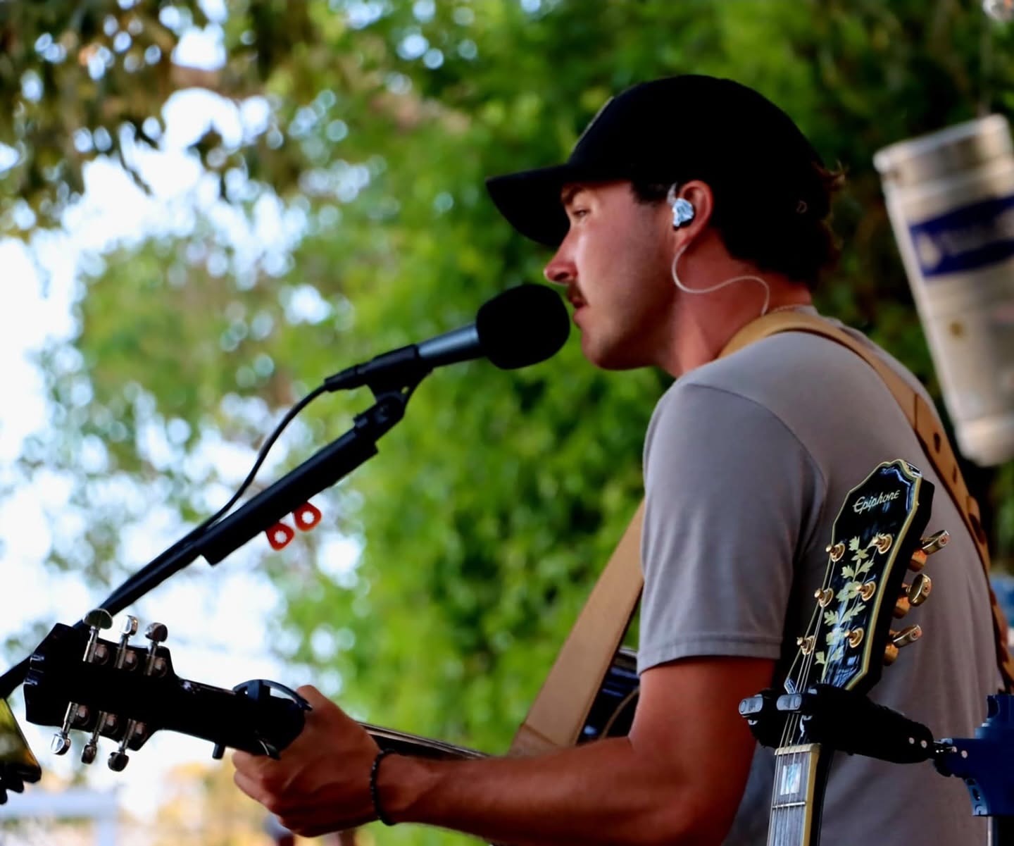 Pierce August singing into the mic outdoors in daylight